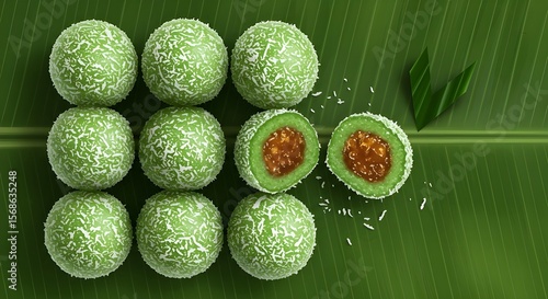 Top-down view of klepon arranged neatly on a banana leaf, green rice cake balls coated in shredded coconut, one cut open showing melted palm sugar inside