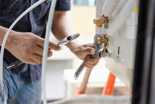 HVAC Technician Using Wrench to Connect AC Pipes, Close-up of Hand Installing Refrigerant Lines on Air Conditioner, Air Conditioning Repair and Installation, Professional Working on Outdoor Unit