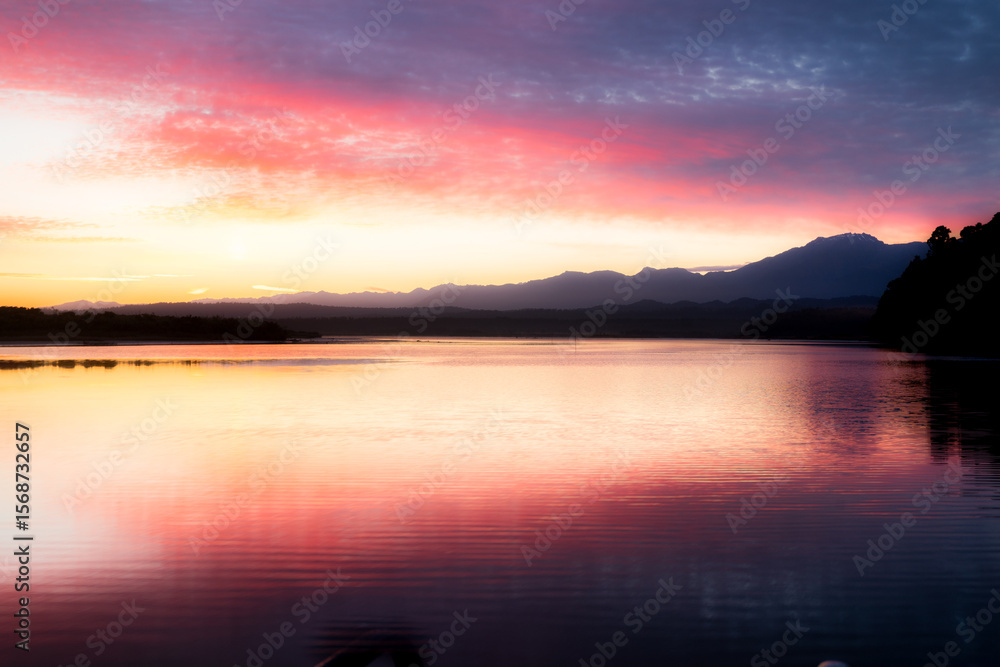 Fototapeta premium The rain forest of the West coast with the Southern Alps in the background (taken at Okarito lagoon) at sunrise