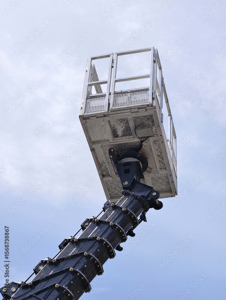 Obraz premium Elevated work platform extends into the sky, showcasing modern construction equipment against a blue backdrop