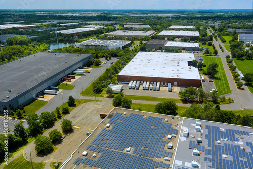 фотографія Solar panels on rooftops several warehouses in lush industrial area captured on sunny day