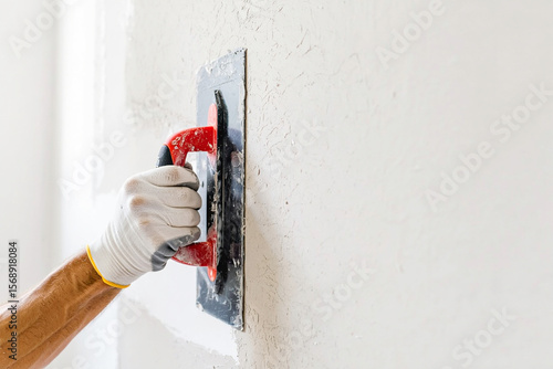 A worker applies plaster to a wall with a trowel during a home renovation project