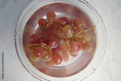 Tableau sur toile Fresh grapes soaking in water for cleaning before serving