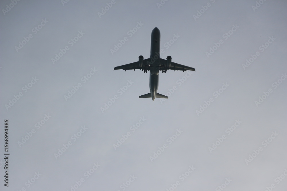 Fototapeta premium Una impresionante vista de un avión tomada desde abajo contra un cielo azul despejado. La aeronave luce elegante y moderna, simbolizando los viajes, la aventura y el espíritu explorador. Viajes