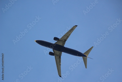 Una impresionante vista de un avión tomada desde abajo contra un cielo azul despejado. La aeronave luce elegante y moderna, simbolizando los viajes, la aventura y el espíritu explorador. Viajes
