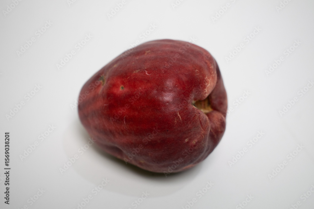 Fototapeta premium Tropical Jamaican guava fruit with deep red skin lies isolated on a clean white surface.