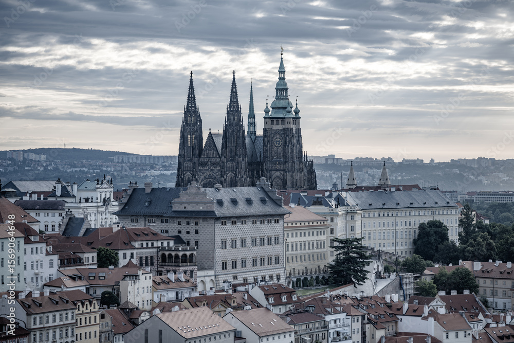 Naklejka premium The early morning sun casts a golden hue over Prague Castle, illuminating its towers and highlighting the historic architecture of the city. A perfect start to the day in Prague.