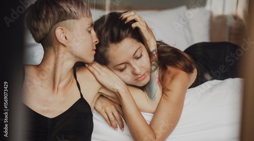 Young tender beautiful lesbian couple in love hugging on the bed
