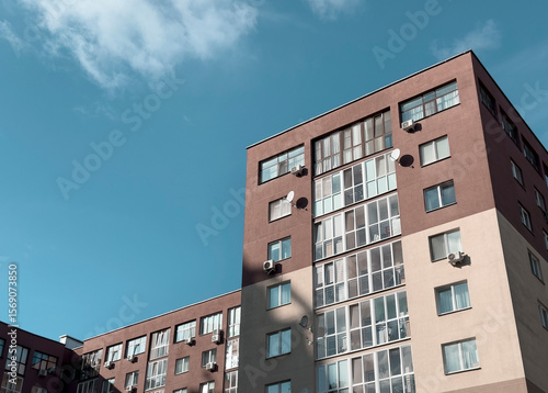 Modern apartment building with a beige and brown facade. Residential structure featuring balconies,