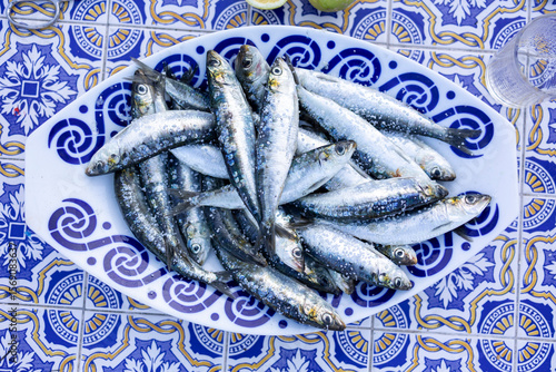 Fresh sardines sprinkled with salt lying on decorative portuguese platter