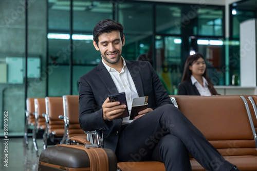 Fotografie Caucasian businessman is using smart mobile phone while waiting in airline busin
