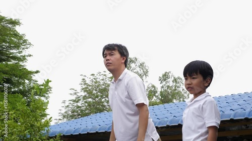 Happy family asian child boy and father play airplane toy outdoor together with fun face in nature background. Happy kid and dad in white shirt enjoy playing in relaxing day.