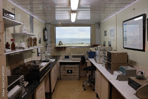 Configuración compacta de laboratorio dentro de un contenedor, idéntica a la utilizada en las expediciones antárticas. El espacio cuenta con un microscopio, equipo científico, una silla y un pequeño