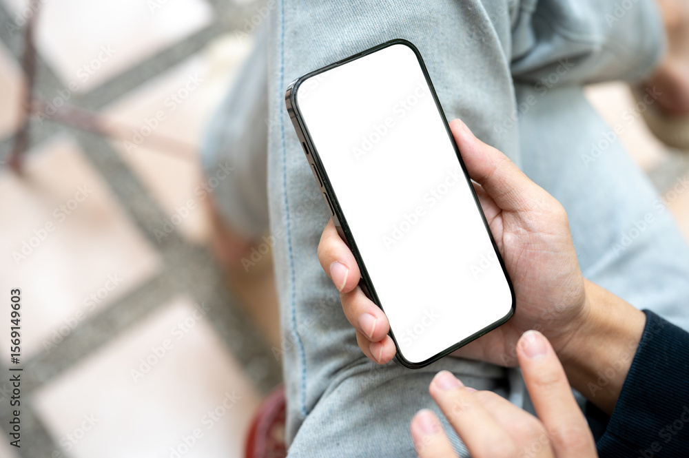 Naklejka premium Hand holding white screen smartphone over lap using application or social media while sits on bench.