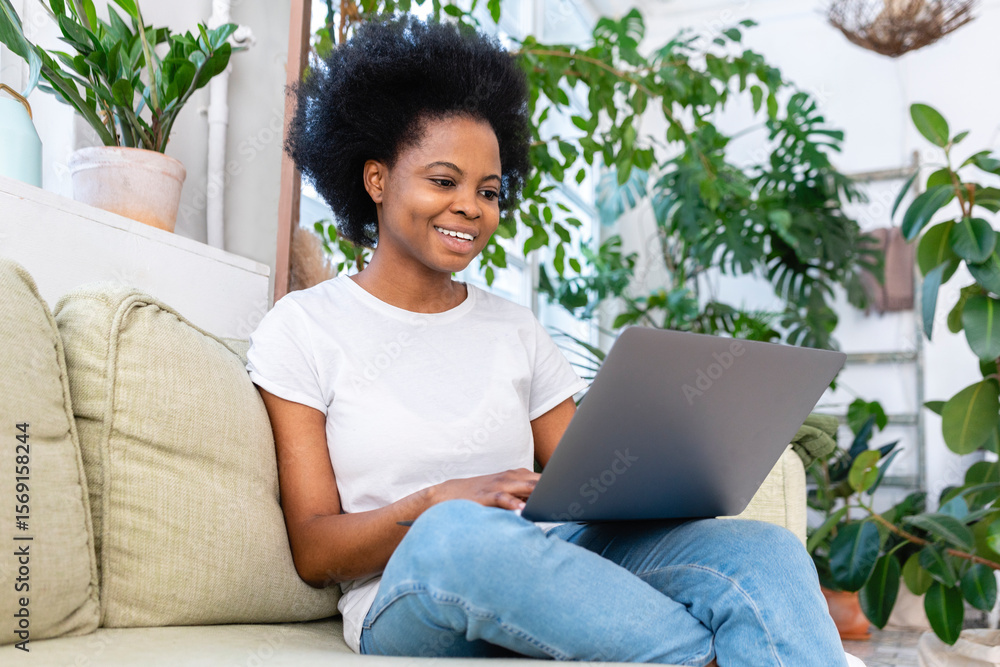 Smiling businesswoman working on laptop on sofa at home Smiling businesswoman working on laptop on sofa at home