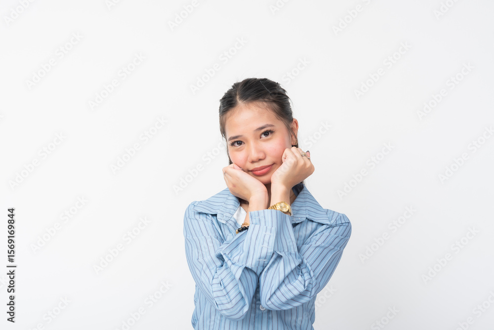 Young Southeast Asian woman wears blue striped long sleeves, acts cute with hands on chin, highlighting her adorable face and shy sweet expression in a minimal white studio shot. Young Southeast Asian woman wears blue striped long sleeves, acts cute with hands on chin, highlighting her adorable face and shy sweet expression in a minimal white studio shot.