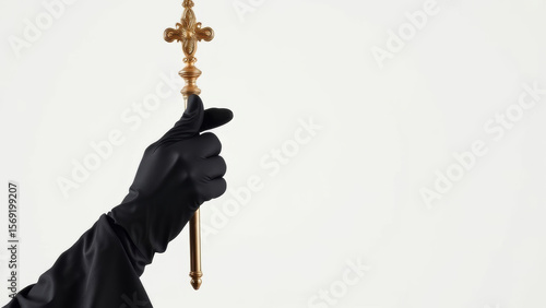 Religious hand gripping golden processional cross, black gloved fingers clasping sacred symbol against pure white backdrop, representing spiritual devotion