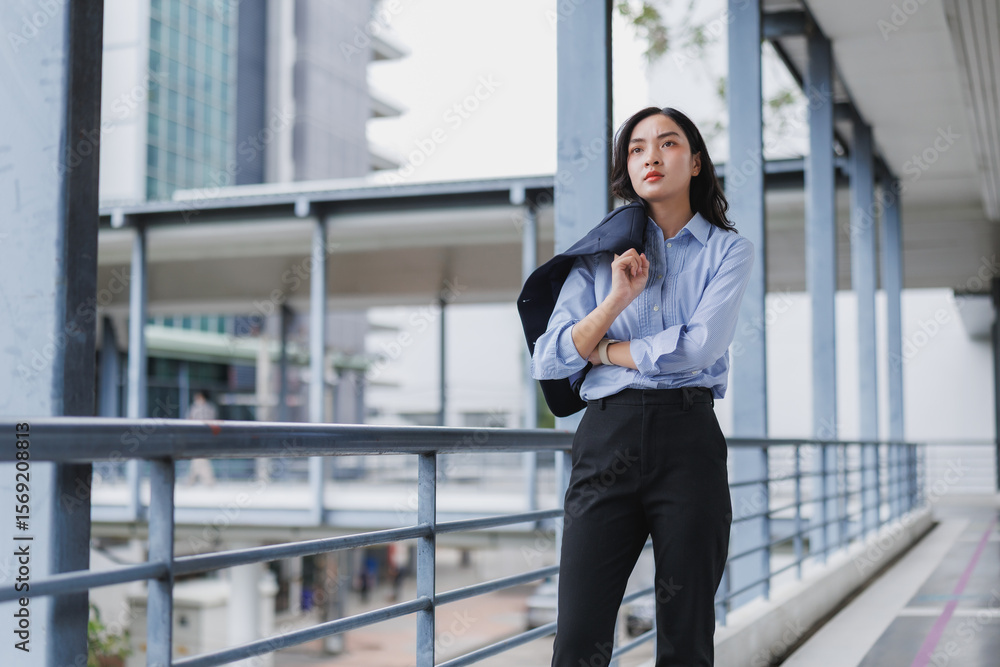 Businesswoman walking in modern city, holding jacket over shoulder Businesswoman walking in modern city, holding jacket over shoulder