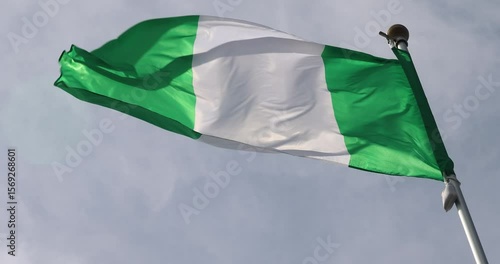 The flag of Nigeria, waving against the blue sky, is the national symbol of Nigeria. The video is presented in 4K format. The Nigerian flag is captured in close-up. Great for news.
