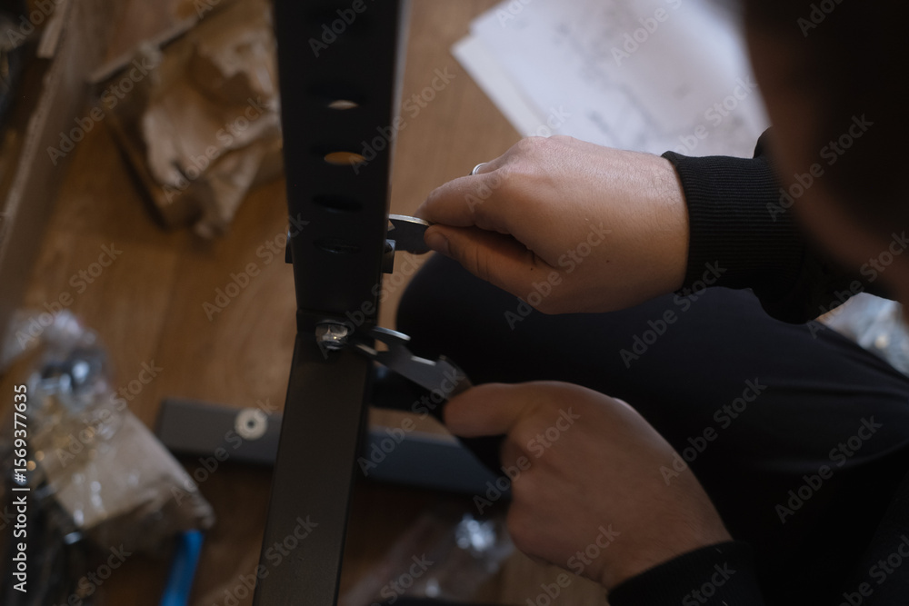 Obraz premium Man assembling fitness equipment at home preparing a gym for daily exercise and healthy lifestyle routines.