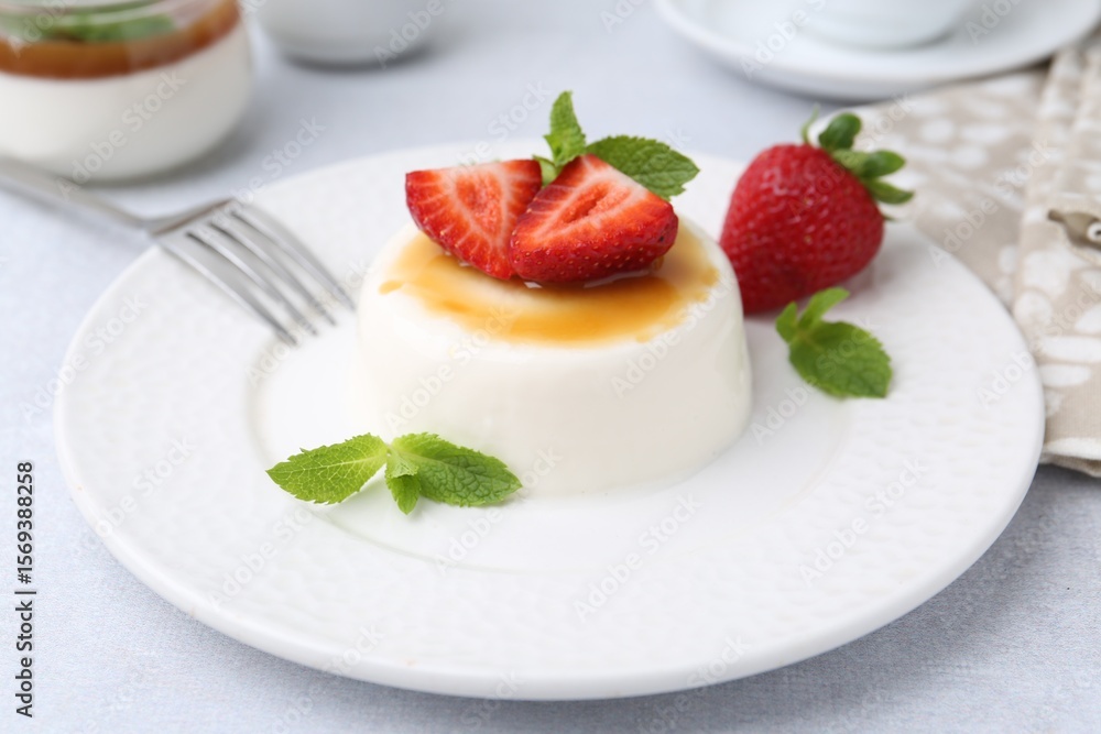 Tasty panna cotta with caramel, strawberries and mint on light table, closeup Tasty panna cotta with caramel, strawberries and mint on light table, closeup