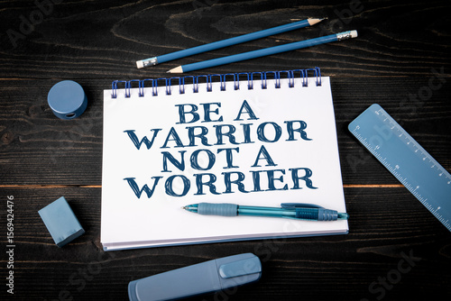 Be a warrior not a worrier. Inspirational Quote on Notepad with Stationery on Desk