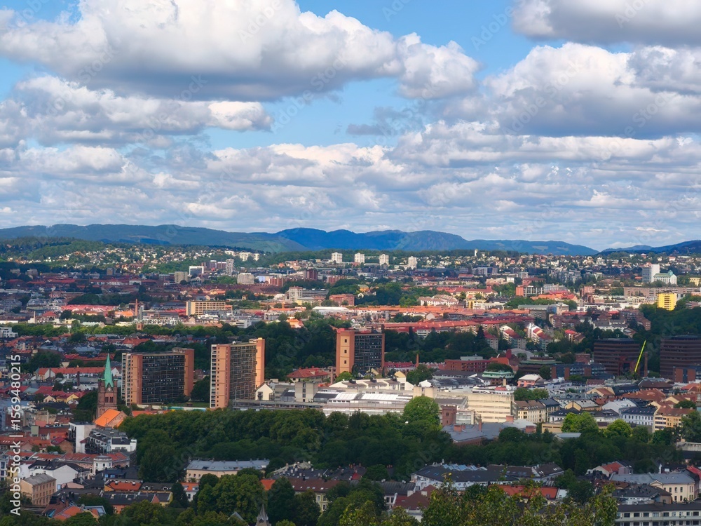 Obraz premium Breathtaking panoramic view of a coastal city from a high mountain viewpoint. City buildings stretch toward the sea under a vast blue sky. Soft morning or sunset light, calm sea horizon