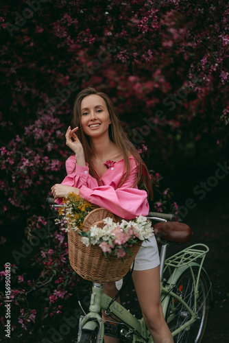 A Young Woman Riding a Bicycle Surrounded by Flowers in a Beautiful Blooming Garden