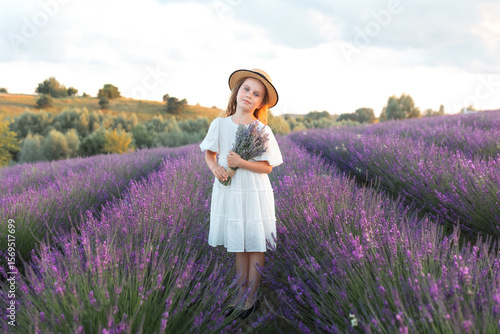 Wallpaper Mural Beautiful young girl in straw boater hat and a white dress collects lavender on lavender field. Portrait cute child girl holding lavender bouquet and stands in the middle of lavender bushes. Provence	 Torontodigital.ca