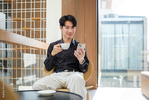 Free Download Young man enjoying coffee while browsing his smartphone in a modern cafe. - GFXLoad