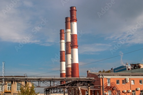 Three tall red-and-white industrial chimneys from a boiler plant or factory in an old industrial district - dramatic urban landscape