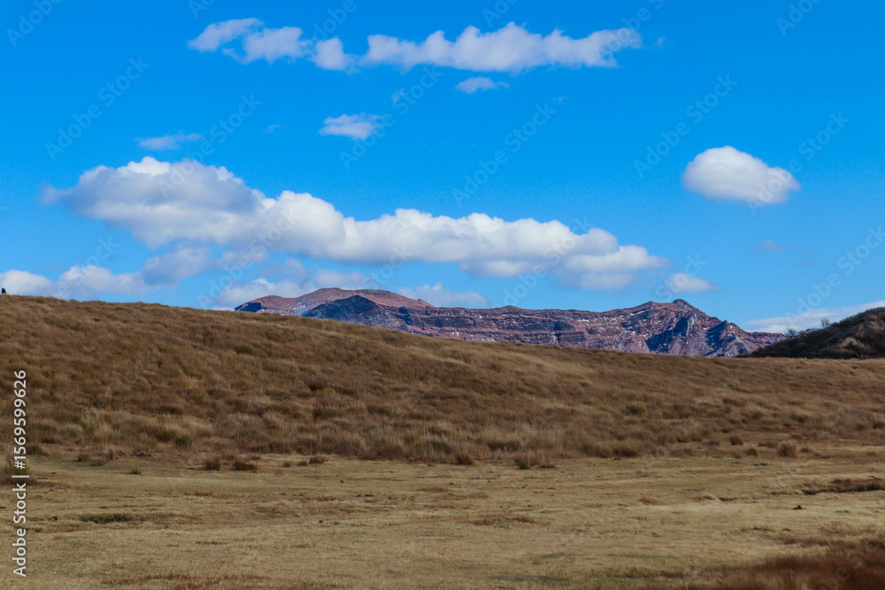 Fototapeta premium Volcanic Landscape with Smoke Rising from Mount Aso under Blue Sky in Japan