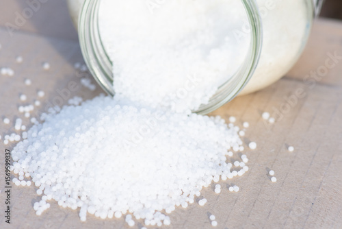Urea granules (carbamide, CO(NH2)2) in glass jar.  Nitrogenous mineral fertilizer for plant nutrition.