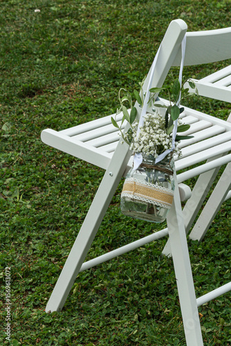 White wooden wedding chair decorated with jar of white flowers