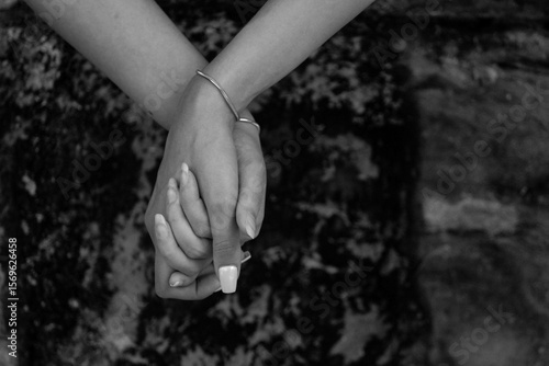 Black and white photo of two female hands holding with matching silver bracelets