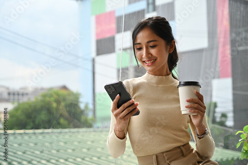 Εκτύπωση καμβά Confident businesswoman in casual office attire holding a cup and phone, taking