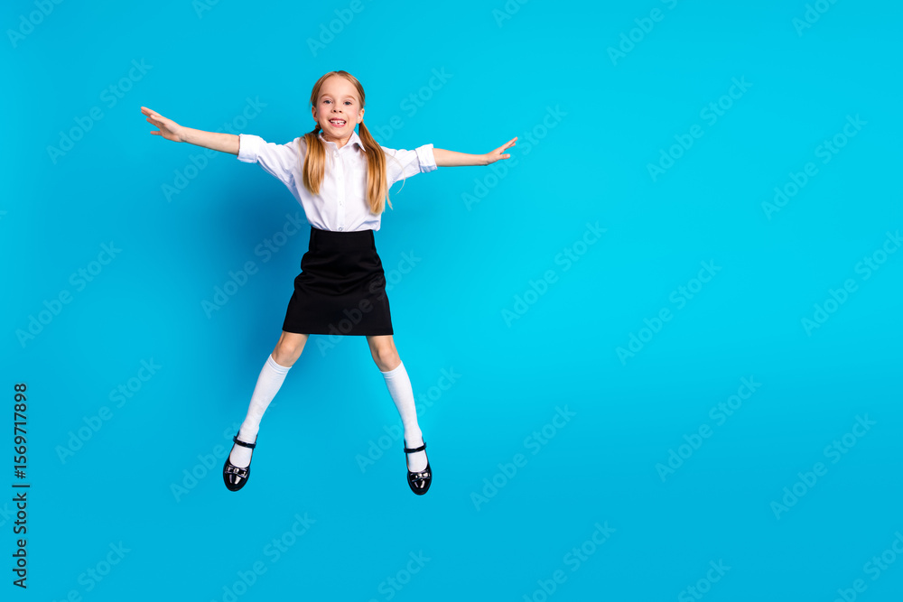 Adorable schoolgirl jumping joyfully in uniform on bright blue background representing education and childhood happiness Adorable schoolgirl jumping joyfully in uniform on bright blue background representing education and childhood happiness