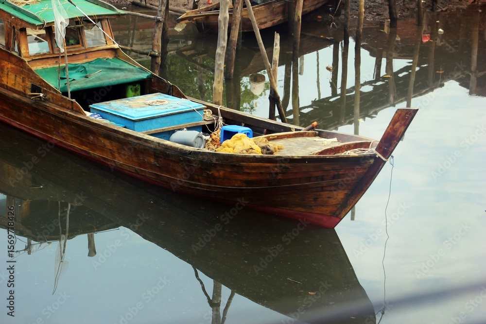 Obraz premium Tranquil Waters: A Wooden Fishing Boat's Reflection
