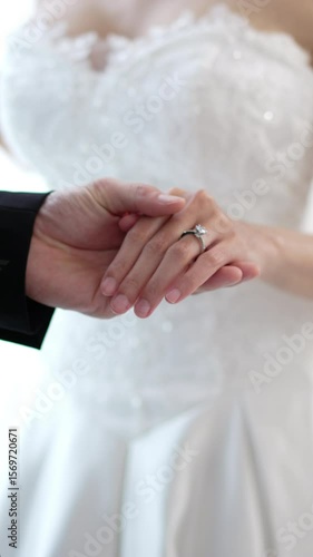 Close up of Romantic groom putting wedding ring on bride finger, elegant asian couple sharing love on special ceremony day