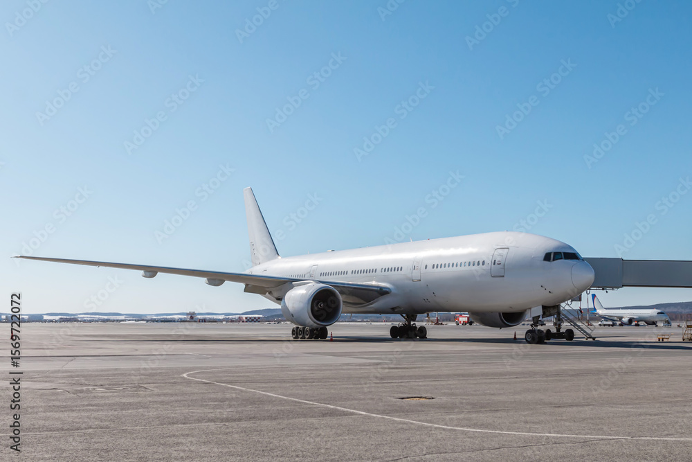 White wide body passenger aircraft at the jetwalk on the airport White wide body passenger aircraft at the jetwalk on the airport