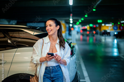 Wallpaper Mural Woman leaning against her car in a parking garage and using a smart phone Torontodigital.ca