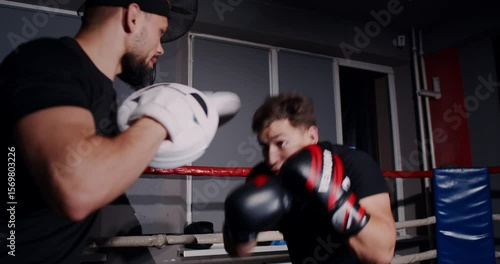 In a dim boxing ring, a determined man showcases his skills in an intense match