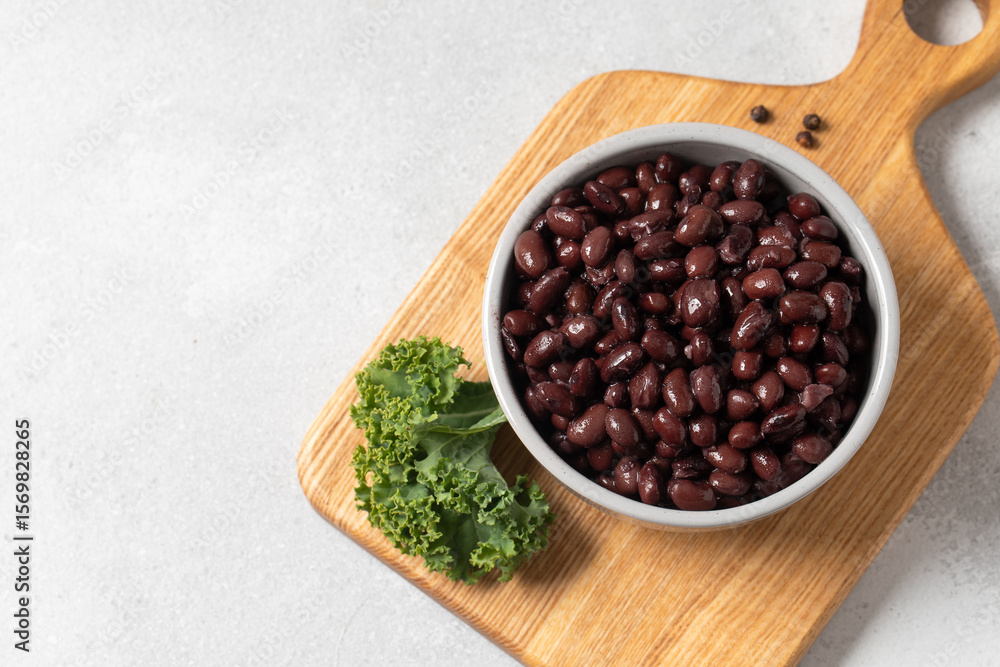 Black beans in a bowl on wooden cutting board with kale leaf Black beans in a bowl on wooden cutting board with kale leaf