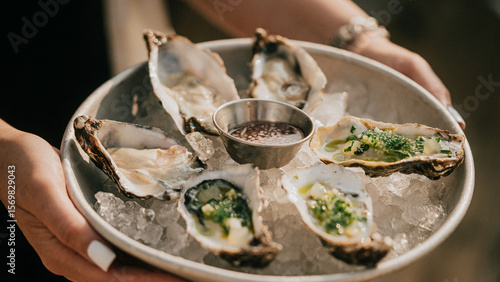 Obraz na plátne A person is holding a plate of oysters with a dipping sauce