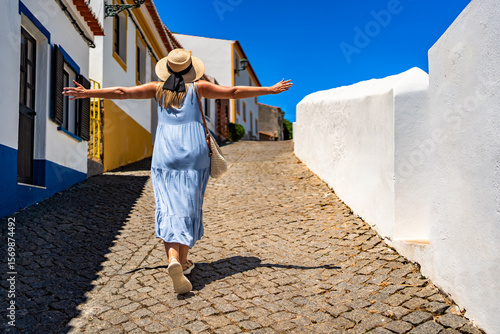 Foto Beautiful middle aged woman tourist walking uphill narrow street in portuguese town on sunny summer day