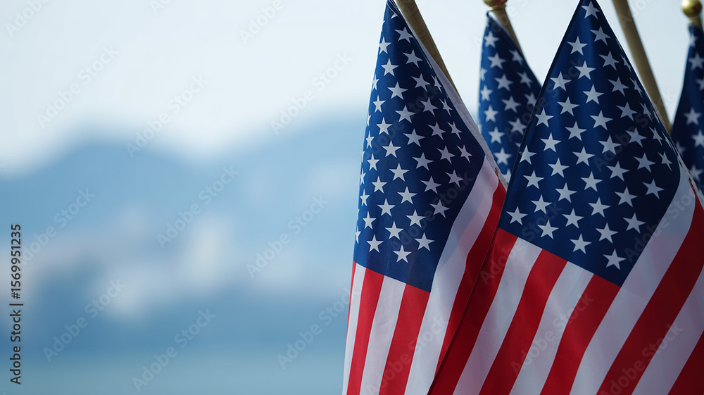Fototapeta premium Close-up view of multiple American flags waving gently against a soft blue sky background.