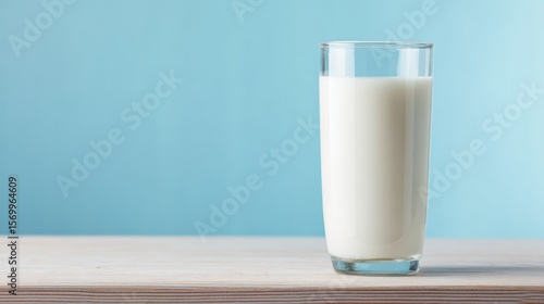 The glass of milk on a wooden table with a soft blue background