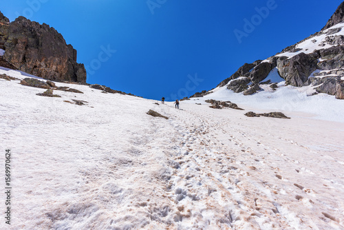 Snowy mountain landscape in the Pyrenees, with rocky peaks, blue sky and alpine lakes along the GR11 trail in Lleida, Spain. Majestic Pyrenees landscape, featuring snow-capped peaks & clear blue skies