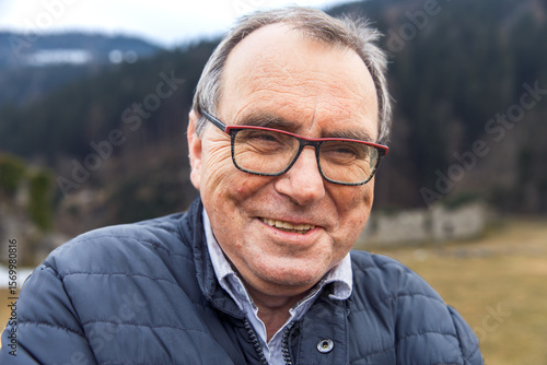 Elderly caucasian male smiling outdoors in a winter jacket
