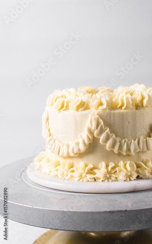 Fotografi Vintage cake on a cake plate, Frilly Cake covered in yellow frosting, process of